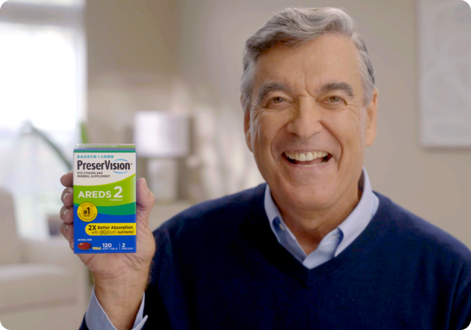 A man in his 60s smiling and holding up a package of PreserVision AREDS 2 Eye Vitamins.